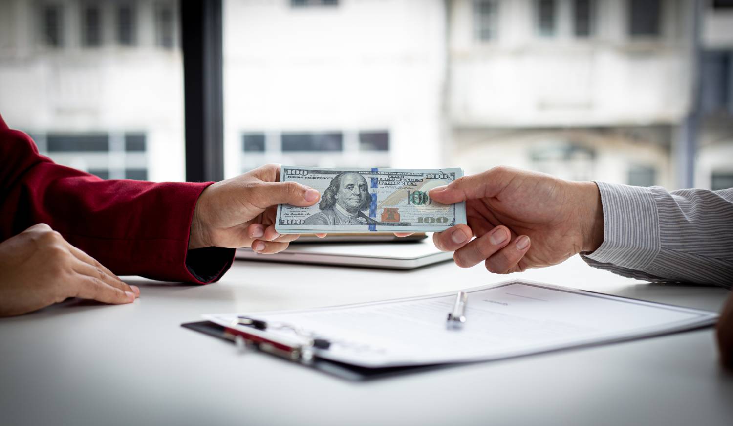 Hands exchanging cash across a table, symbolizing foreclosure funds recovery and equity claim payout.